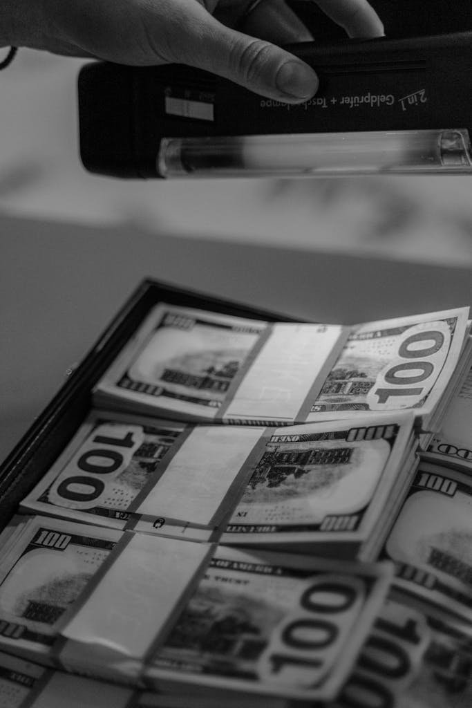 A black and white close-up of hundred dollar bills examined under UV light.
