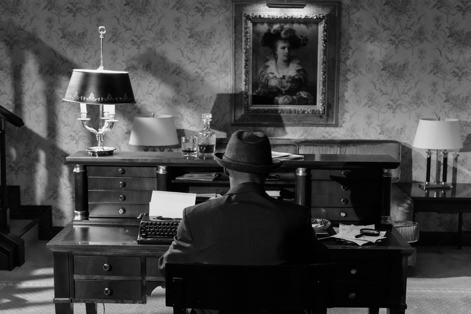 A vintage monochrome scene featuring a detective in a fedora hat at a typewriter, evoking classic noir mystery.